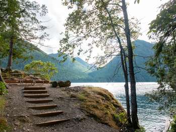 A small set of wooden stairs leads to a picnic table overlooking a lake.