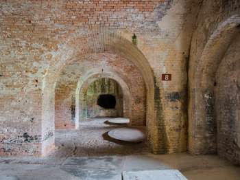 White brick interior walls and archways of Fort Pickens. A brown metal sign with the number, 