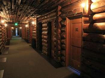 A hallway of log walls and ceilings lit by bulbs on candles