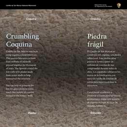 Against a beige background of the tiny shells that make up the coquina stone are 2 columns of white text: on the left, English; on the right, Spanish.  Crumbing Coquina. Fort Matanzas was built using coquina, a local limestone. This porous limestone is made from millions of seashells pressed together for thousands of years. The Spanish coated the fort walls with plaster made from oyster shells to help waterproof the structure.  You can help us preserve the fort for generations to come: touch this sample of coquina instead of the historic walls.  End of Text  In the center of the panel, between the 2 columns of text, a long rectangular inset container with touchable material. On the top half, light tan, coquina; on the lower half, greyish-white plaster.  Beyond the panel is a shrub and tree covered ancient sand dune. To the left, a sidewalk leading to the ferry dock, beyond that another sidewalk leading back to the visitor center. To the left and behind is the visitor center.  [End of Message]
