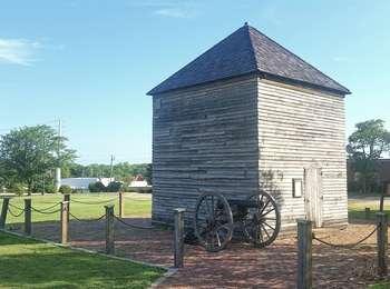 blockhouse with cannon in front and wooden posts with chain surrounding the building