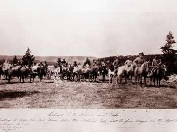 A line of men on horses and a wagon pulled by mules in a meadow