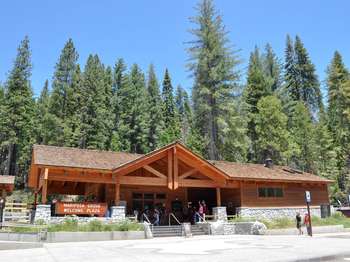 A wooden building with a stone foundation has a sign that reads,