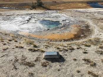 A small, blue pool sits in a small, gray ground depression.