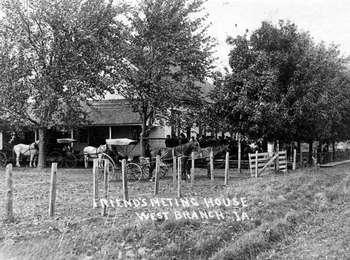 A black and white photo shows horses, carriages, and people gathered just outside a Friends Meetinghouse.