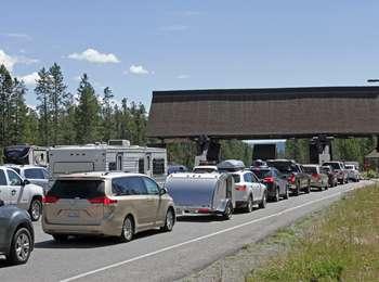 Three lines of traffic approach a wide drive-thru entry way with booths