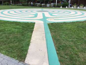 A flat stone two-colored maze cuts into grass