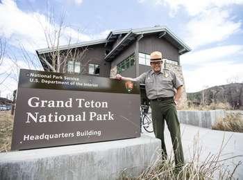 Superintendent Vela standing next to park headquarters sign with the building in the background.