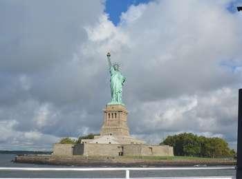 The bright green patina of Lady Liberty stands out in bright contrast to the cumulus clouds behind her.