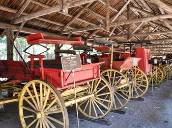 Old, red wagons are lined up in this shed that is open for public viewing.