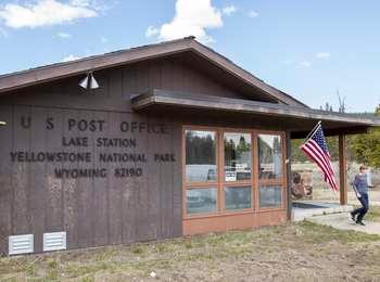 Peeling paint on a wood-paneled building with large windows, a US flag, and lettering 