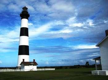 Bodie Island Lighthouse with a cloudy blue sky.