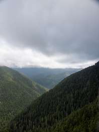 A view of green mountainsides with a heavy layer of clouds above.