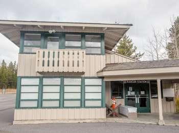 A two-story building with windows and a porch over an entrance with double doors
