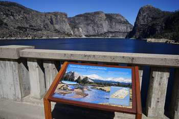 A large body of water is seen in the distance behind a wayside exhibit.