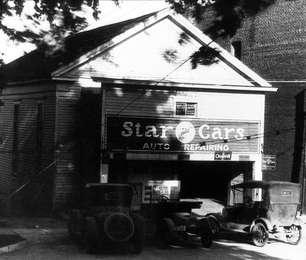 Black and white photo shows second site of Friends Meetinghouse as auto repair garage with cars parked out front.