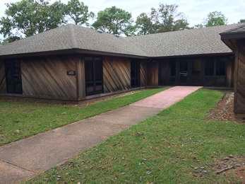 Brown wooden headquarters building with a concrete walkway leading to the front entrance