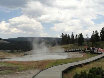 People stand on the boardwalk and watch the activity of the hot spring.