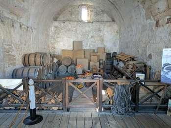 vaulted ceiling room containing barrels, ropes, baskets, food, and other supplies