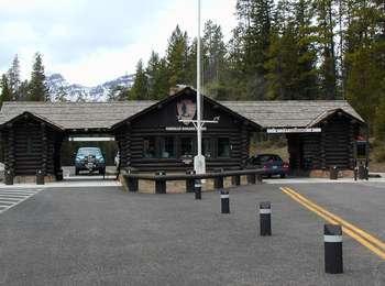 A log cabin with drive-thru carports on both sides in with mountains in the background