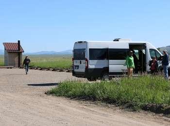 Visitors unloading from a van at the South Mormon Row Parking area with a vault toilet to the left.