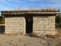 Looking at the outside of a small sod home with a roof composed of sod, wood, and living plants