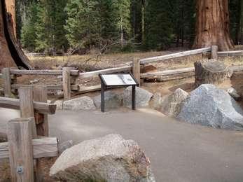 Wayside exhibit in front of a wooden fence on paved trailĀ