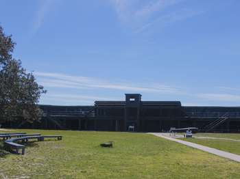 Black battery building and blue sky in the background. Green grass in the foreground.