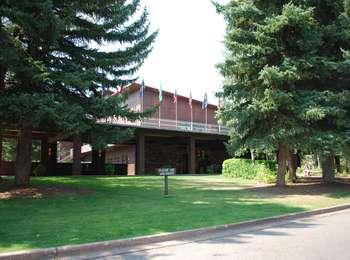 Walkway to the front of the Jackson Lake Lodge with grass lawn and large spruce trees