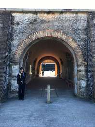 Brick archway in the side of the brick Fort Pickens scarp wall. A man in a dark blue uniform stands to the left of the archway.
