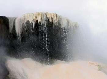 Water drips over a travertine shelf shrouded in steam