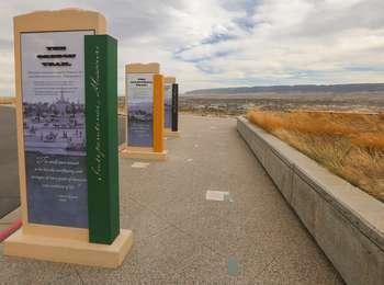 Wide stone pathway with tall interpretive wayside signs that overlooks the small city of Casper