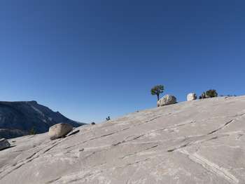 Several large boulders randomly sit on an expanse of granite bedrock, which is streaked with lines and cracks.