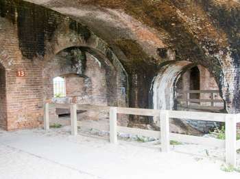 Three fort interior brick archways. A brown metal sign with the number,