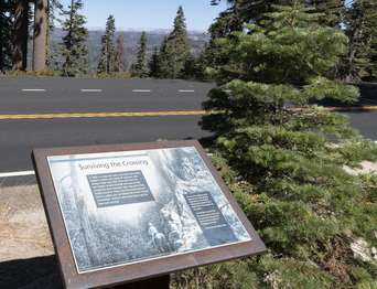 A wayside exhibit stands near a roadside pullout.