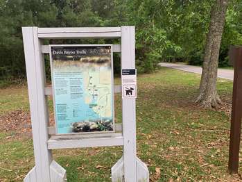 A wood framed orientation panel stands between a road intersection and the forest.