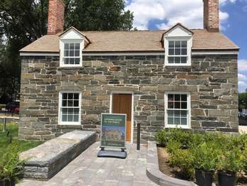 A small two story brick bulding with two chimneys and four windows