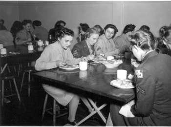 In this black and white photograph, WACs eat in the women’s mess hall.
