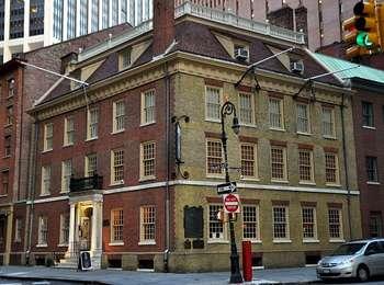 The original red brick and stone colonial era gathering place still stands proudly at the corner of Pearl and Broad Streets in downtown Manhattan.