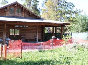 Jenny Lake Store with visitors sitting at a picnic table outside. Orange fencing closes off the construction area.