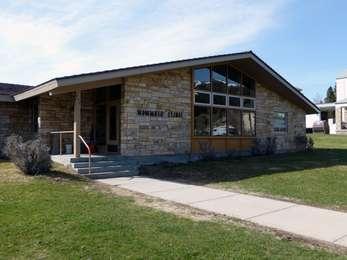 A sidewalk leads to a stone building with low roof and windows