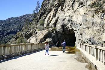 A few people follow a paved path that leads into a cave-like tunnel.