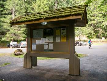 A roofed bulletin board with informational signs attached.