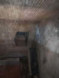 Brick fort walls with a small opening about two feet from the ground in one of the walls.
