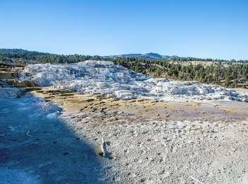 White travertine terraces with mountains in the background