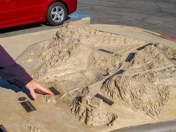 A visitor's hand points at a feature on the three dimensional tactile map of Lands End.