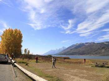 Visitors at Mud Flats picnic area enjoying the fall colors of the aspens on the edge of Jackson Lake. The Teton Range stretches to the south across the lake.