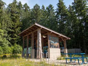 An outdoor exhibit space with photos and informational signage. Picnic table and bike seat.