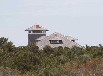 Shake shingle roofs of the historic Little Kinnakeet US Life-Saving Service Station visible above the woods.