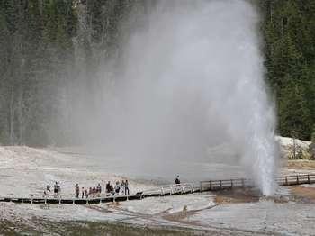 People watching the eruption of a cone geyser from a nearby boardwalk.